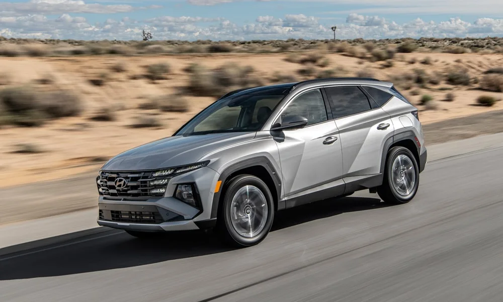 Фото Hyundai Tucson (2024) — вид спереди, фото 3. Кузов в серебристом цвете: рисунок оптики и решётки задаёт узнаваемое «лицо» модели. Рисунок ходовых огней — подпись модели, по нему её узнают в потоке Hyundai Tucson (2024) — вид спереди, фото 3