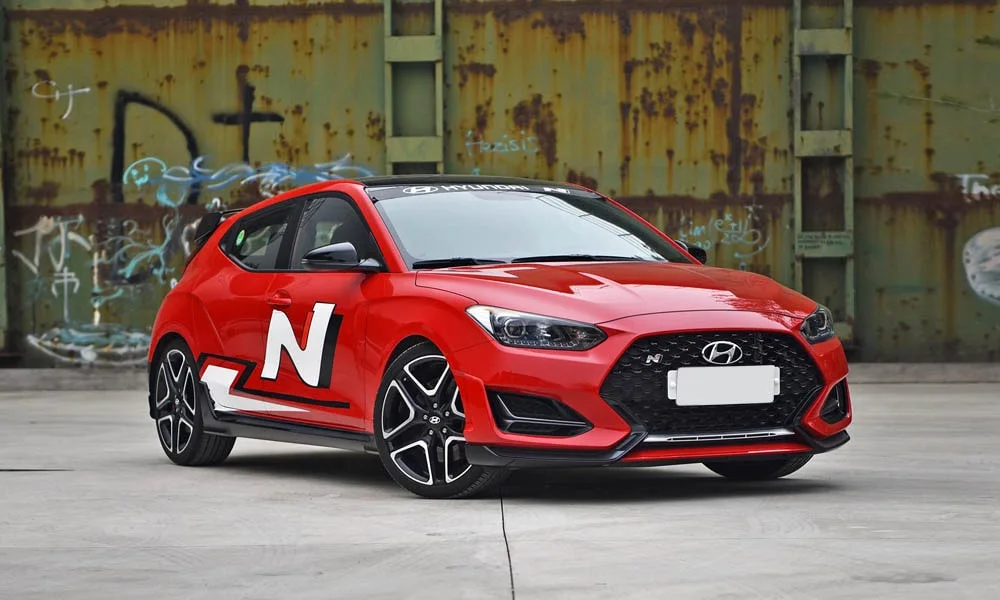 Фото Hyundai Veloster N (2024) — вид спереди, фото 3. Анфас: пропорции капота, посадка кузова и графика ходовых огней. Дневные ходовые огни включаются автоматически с запуском Hyundai Veloster N (2024) — вид спереди, фото 3