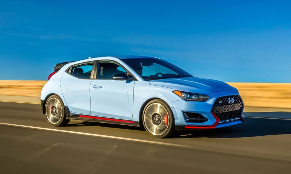 Фото Hyundai Veloster N (2024) — вид спереди, фото 6. Синий кузов, строгая симметрия оптики — базовый ракурс знакомства с дизайном. Дневные ходовые огни включаются автоматически с запуском Hyundai Veloster N (2024) — вид спереди, фото 6