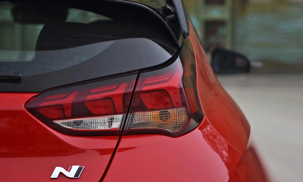 Фото Hyundai Veloster N (2024) — вид сзади, фото 4. Корма в красном цвете: графика фонарей и пластика пятой двери Hyundai Veloster N (2024) — вид сзади, фото 4