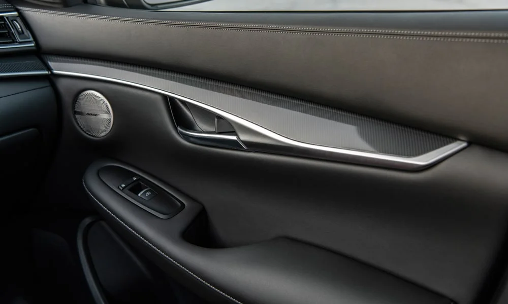 Фото Infiniti QX50 (2024) — дверная карта. Подлокотник, динамик и блок стеклоподъёмников. Решётка динамика в двери — часть штатной акустики Infiniti QX50 (2024) — дверная карта