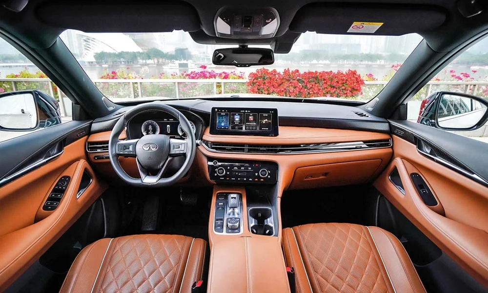 Фото Infiniti QX60 (2024) — передняя панель. Панель в коричневой отделке — видна компоновка экранов и органов управления. Мягкие материалы верхнего яруса и вставки задают уровень интерьера Infiniti QX60 (2024) — передняя панель