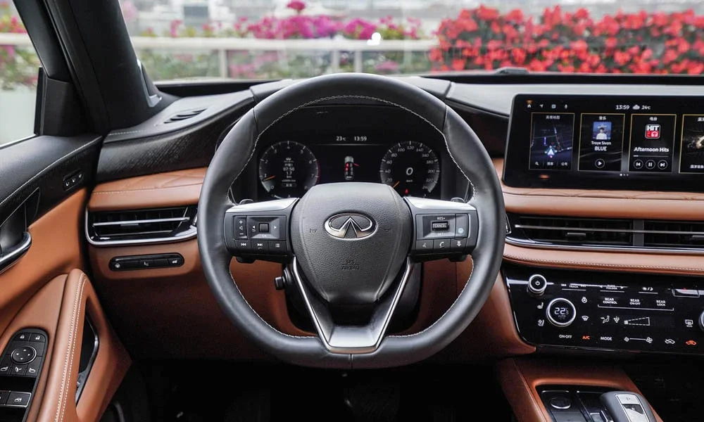 Фото Infiniti QX60 (2024) — руль. Обшивка обода и компоновка спиц крупным планом. Клавиши на спицах управляют медиа, круизом и ассистентами — руки остаются на руле Infiniti QX60 (2024) — руль