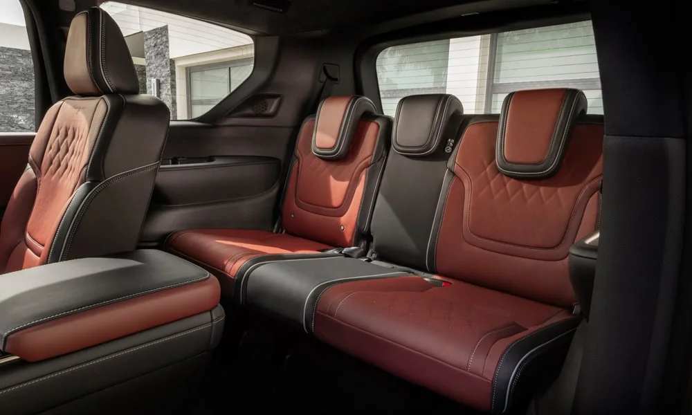 Фото Infiniti QX80 (2024) — задние сиденья, фото 2. Посадка второго ряда: подголовники и подлокотник. Плоский пол упрощает посадку втроём Infiniti QX80 (2024) — задние сиденья, фото 2