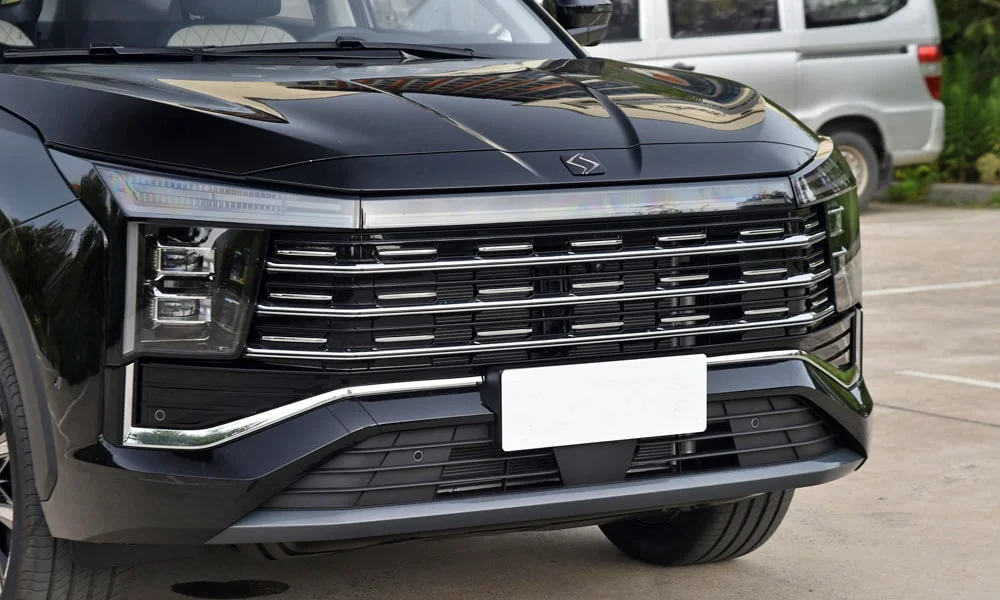 Фото JAC X8 Plus (2024) — решётка радиатора. Рисунок решётки: сетка, ламели или глухая панель у электроверсий. За решёткой у многих комплектаций стоит радар адаптивного круиз-контроля JAC X8 Plus (2024) — решётка радиатора
