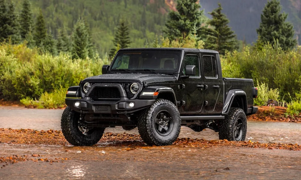 Фото Jeep Gladiator (2024) — вид спереди, фото 8. Кузов в чёрном цвете: рисунок оптики и решётки задаёт узнаваемое «лицо» модели. Рисунок ходовых огней — подпись модели, по нему её узнают в потоке Jeep Gladiator (2024) — вид спереди, фото 8
