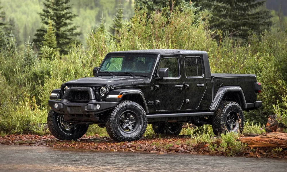 Фото Jeep Gladiator (2024) — вид спереди, фото 12. Чёрный кузов, строгая симметрия оптики — базовый ракурс знакомства с дизайном. Рисунок ходовых огней — подпись модели, по нему её узнают в потоке Jeep Gladiator (2024) — вид спереди, фото 12