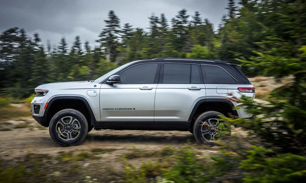 Фото Jeep Grand Cherokee (2024) — вид сбоку. Профиль кузова: колёсная база, свесы и линия остекления. Хромированные или чёрные молдинги окон отличают комплектации Jeep Grand Cherokee (2024) — вид сбоку