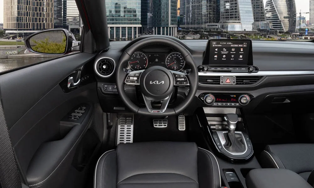 Фото KIA Cerato — передняя панель. Панель в красно-чёрной отделке — видна компоновка экранов и органов управления. Минимум физических кнопок — ставка на экранное управление KIA Cerato — передняя панель