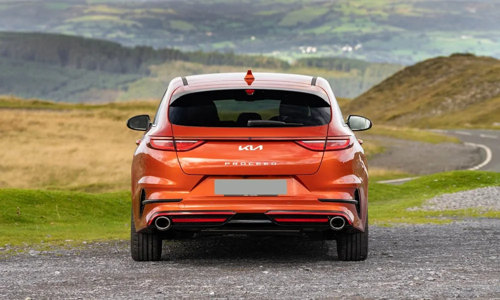Фото KIA ProCeed (2024) — вид сзади, фото 4. Оранжевый кузов сзади — фонари и бампер определяют ночной образ модели. Насадки выхлопа или их имитация внизу бампера различают версии KIA ProCeed (2024) — вид сзади, фото 4