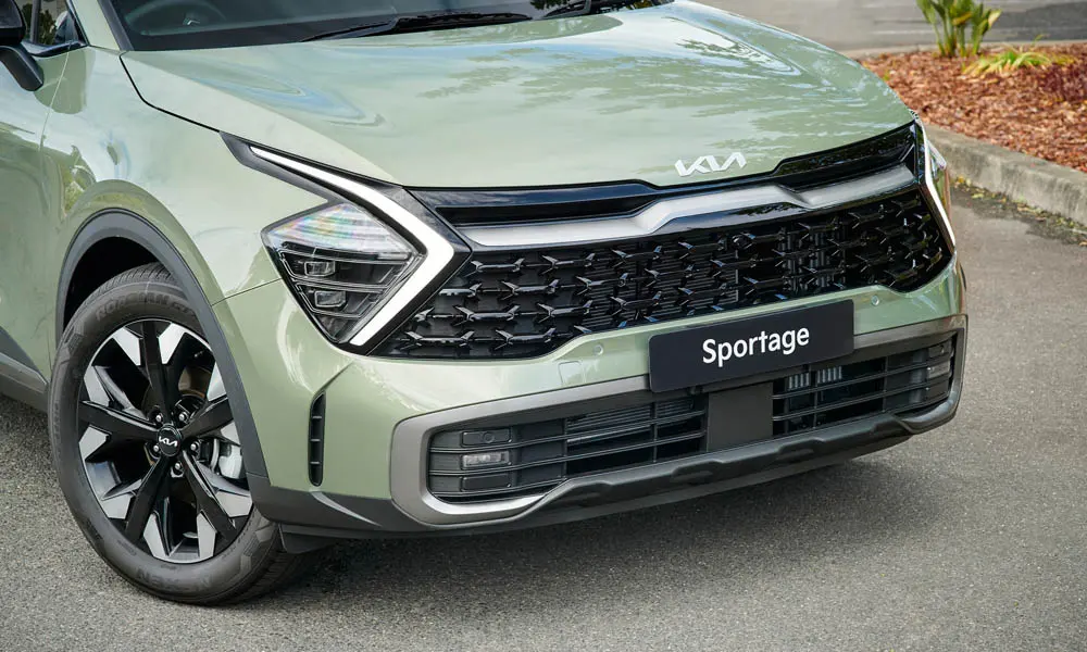 Фото KIA Sportage (2022) — вид спереди, фото 7. Передок в зелёном исполнении — крупная светотехника и выразительный бампер. Рисунок ходовых огней — подпись модели, по нему её узнают в потоке KIA Sportage (2022) — вид спереди, фото 7
