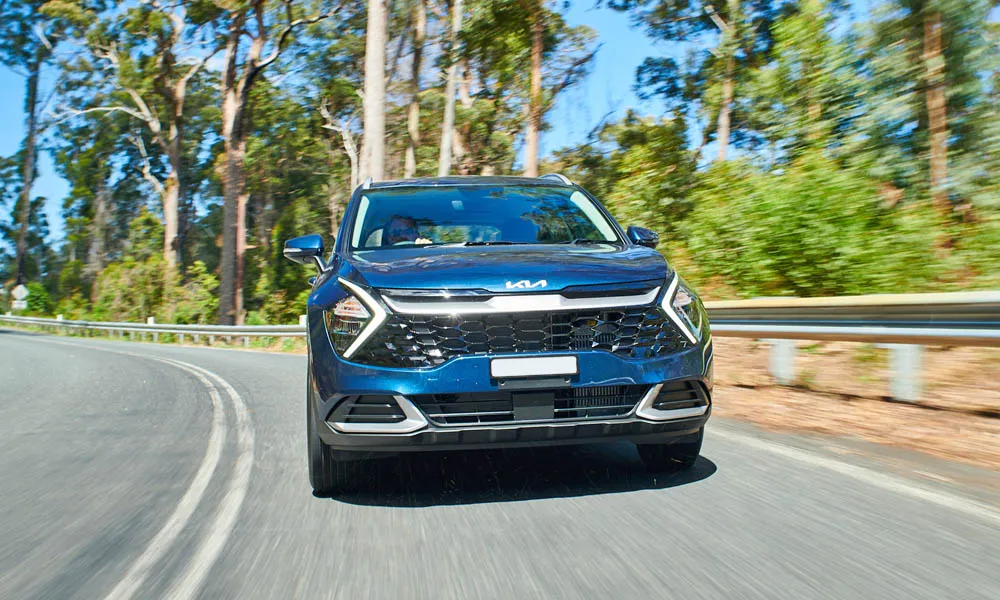 Фото KIA Sportage (2022) — вид спереди, фото 12. Кузов в синем цвете: рисунок оптики и решётки задаёт узнаваемое «лицо» модели KIA Sportage (2022) — вид спереди, фото 12