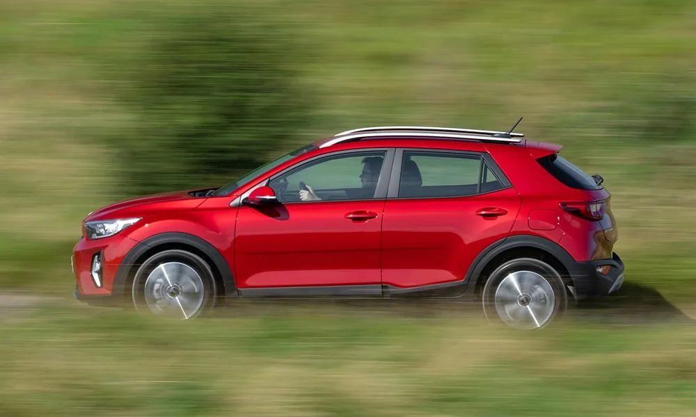 Фото KIA Stonic — вид сбоку, фото 3. Профиль в красном цвете: соотношение колёсной базы и свесов. Хромированные или чёрные молдинги окон отличают комплектации KIA Stonic — вид сбоку, фото 3