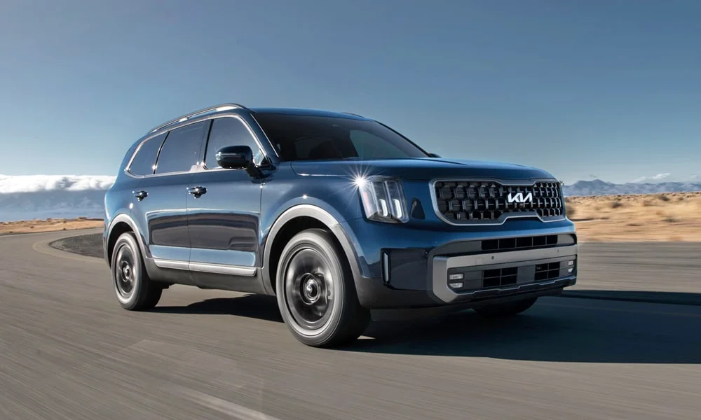 Фото KIA Telluride (2024) — вид спереди, фото 6. Передок в синем исполнении — крупная светотехника и выразительный бампер. Рисунок ходовых огней — подпись модели, по нему её узнают в потоке KIA Telluride (2024) — вид спереди, фото 6
