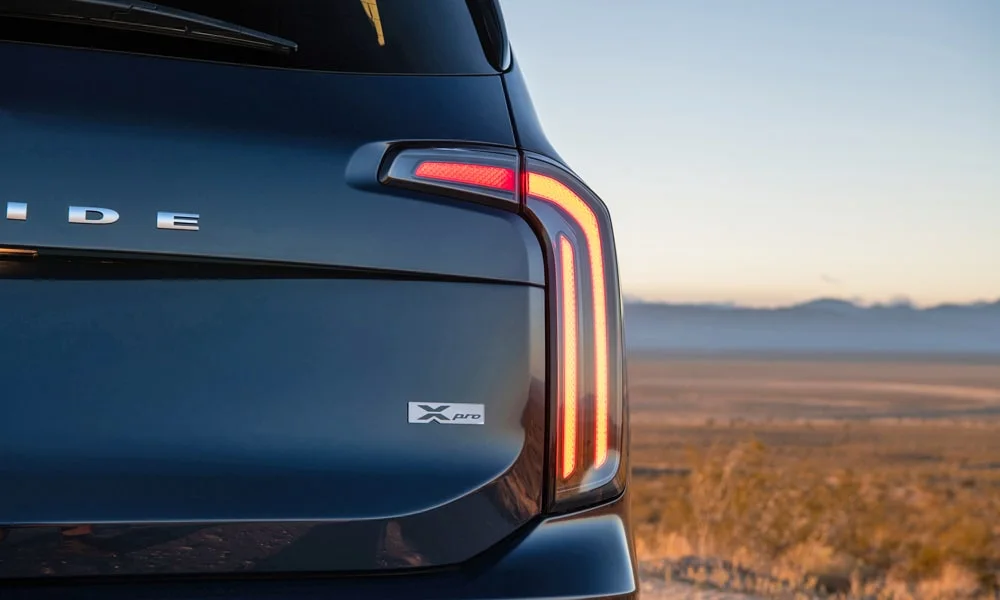 Фото KIA Telluride (2024) — вид сзади, фото 4. Корма в синем цвете: графика фонарей и пластика пятой двери. Светодиодная полоса или раздельные секции — задняя оптика стала главным украшением кормы KIA Telluride (2024) — вид сзади, фото 4