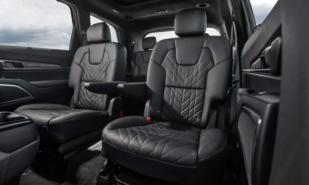 Фото KIA Telluride (2024) — задние сиденья. Посадка второго ряда: подголовники и подлокотник. Спинки складываются под длинные грузы у большинства версий KIA Telluride (2024) — задние сиденья