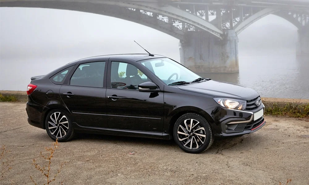 Фото LADA Granta Sportline Лифтбек (2023) — вид сбоку. Профиль в чёрном цвете: соотношение колёсной базы и свесов. Хромированные или чёрные молдинги окон отличают комплектации LADA Granta Sportline Лифтбек (2023) — вид сбоку