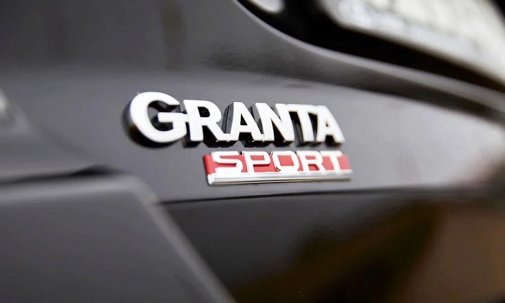 Фото LADA Granta Sport (2023) — эмблема, фото 2. Логотип марки крупным планом. Шильдик версии на корме помогает отличать комплектации LADA Granta Sport (2023) — эмблема, фото 2