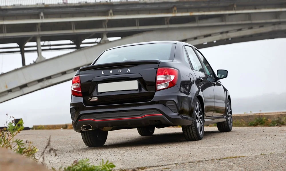 Фото LADA Granta Sport (2023) — вид сзади. Корма в чёрном цвете: графика фонарей и пластика пятой двери. Светодиодная полоса или раздельные секции — задняя оптика стала главным украшением кормы LADA Granta Sport (2023) — вид сзади