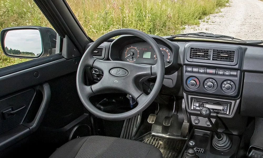 Фото LADA Niva Legend Бортовая — руль. Обшивка обода и компоновка спиц крупным планом. Клавиши на спицах управляют медиа, круизом и ассистентами — руки остаются на руле LADA Niva Legend Бортовая — руль