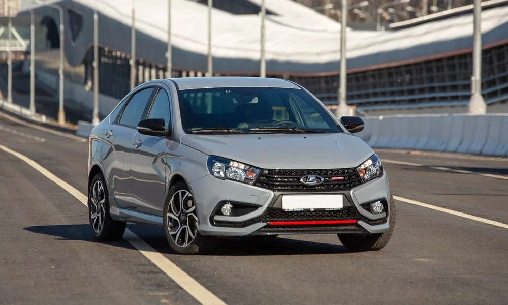 Фото LADA Vesta Sport (2026) — вид спереди, фото 5. Серый кузов, строгая симметрия оптики — базовый ракурс знакомства с дизайном. Дневные ходовые огни включаются автоматически с запуском LADA Vesta Sport (2026) — вид спереди, фото 5