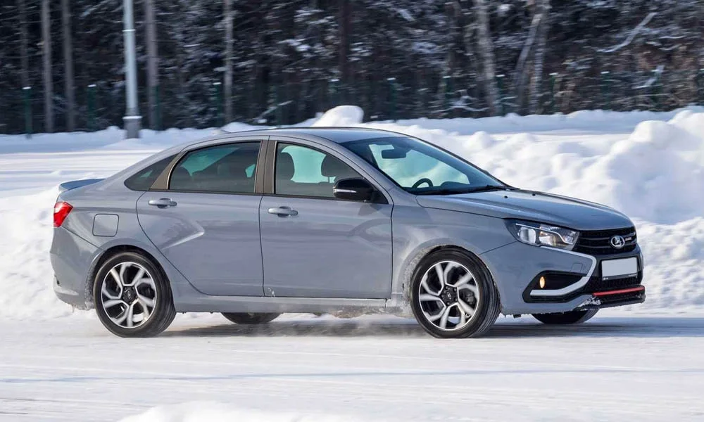 Фото LADA Vesta Sport (2026) — вид сбоку. Сбоку читаются линия остекления и характер выштамповок на сером кузове. Хромированные или чёрные молдинги окон отличают комплектации LADA Vesta Sport (2026) — вид сбоку