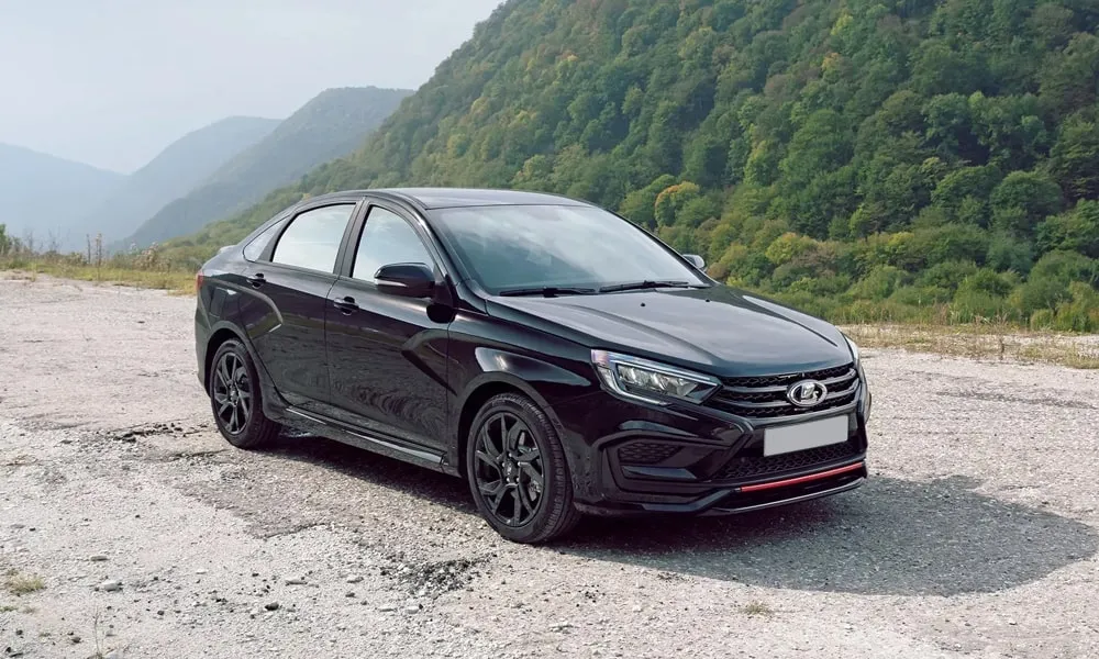 Фото LADA Vesta Sportline (2023) — вид спереди, фото 3. Кузов в чёрном цвете: рисунок оптики и решётки задаёт узнаваемое «лицо» модели. Рисунок ходовых огней — подпись модели, по нему её узнают в потоке LADA Vesta Sportline (2023) — вид спереди, фото 3