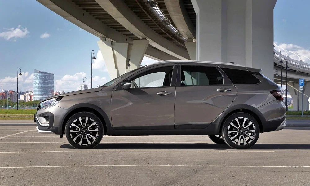 Фото LADA Vesta SW Cross (2023) — вид сбоку. Сбоку читаются линия остекления и характер выштамповок на сером кузове. Хромированные или чёрные молдинги окон отличают комплектации LADA Vesta SW Cross (2023) — вид сбоку