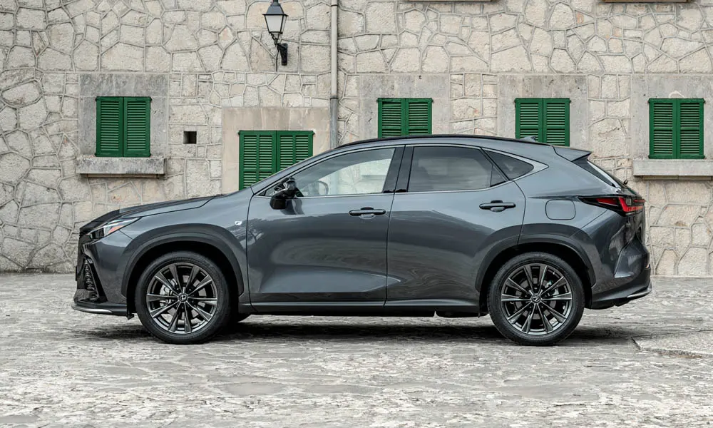 Фото Lexus NX 450h (2024) — вид сбоку. Серый кузов в профиль — пропорции, высота посадки и дизайн дисков. Хромированные или чёрные молдинги окон отличают комплектации Lexus NX 450h (2024) — вид сбоку