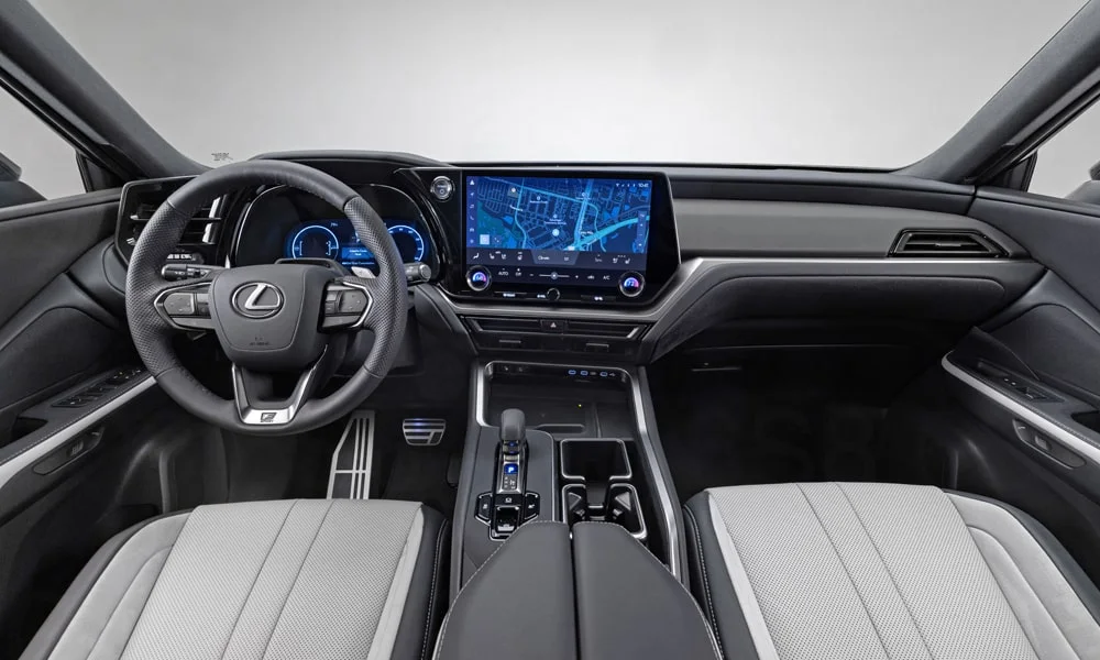 Фото Lexus TX 500h — передняя панель. Панель в светло-серой отделке — видна компоновка экранов и органов управления. Минимум физических кнопок — ставка на экранное управление Lexus TX 500h — передняя панель
