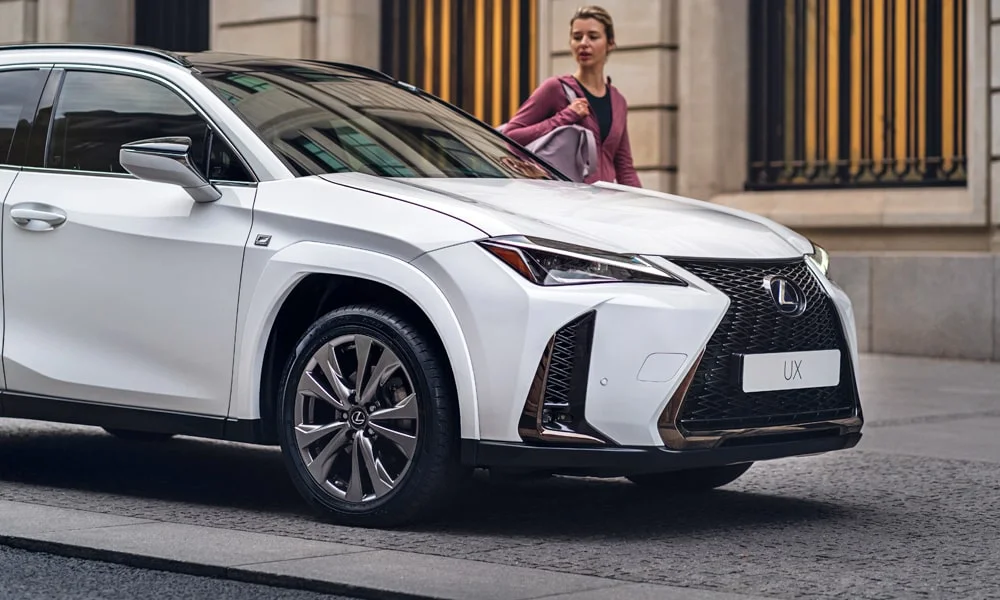 Фото Lexus UX 200 (2024) — вид спереди, фото 4. Передок в белом исполнении — крупная светотехника и выразительный бампер. Дневные ходовые огни включаются автоматически с запуском Lexus UX 200 (2024) — вид спереди, фото 4