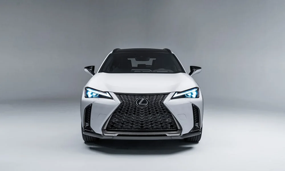 Фото Lexus UX 200 (2024) — вид спереди, фото 5. Кузов в белом цвете: рисунок оптики и решётки задаёт узнаваемое «лицо» модели Lexus UX 200 (2024) — вид спереди, фото 5