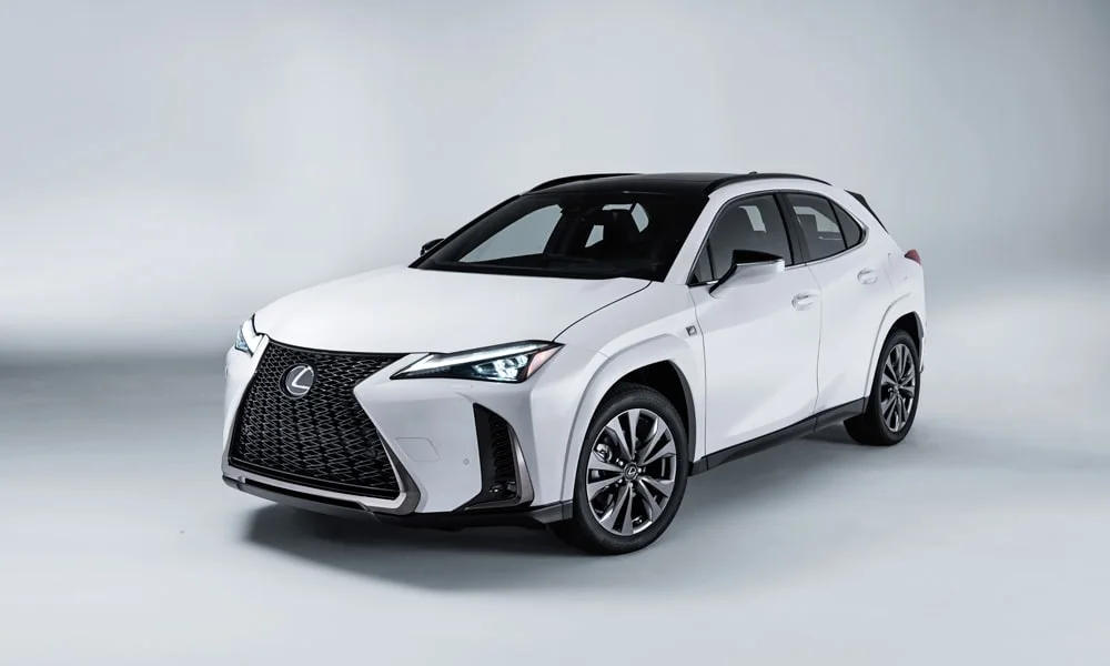 Фото Lexus UX 200 (2024) — вид спереди, фото 6. Передок в белом исполнении — крупная светотехника и выразительный бампер. Рисунок ходовых огней — подпись модели, по нему её узнают в потоке Lexus UX 200 (2024) — вид спереди, фото 6