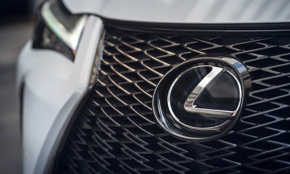 Фото Lexus UX 200 (2024) — решётка радиатора. Фирменный рисунок облицовки — визитная карточка марки. За решёткой у многих комплектаций стоит радар адаптивного круиз-контроля Lexus UX 200 (2024) — решётка радиатора