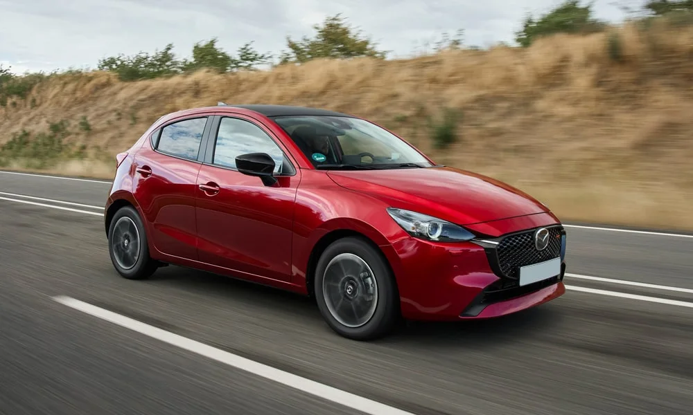Фото Mazda 2 (2024) — вид спереди, фото 4. Анфас: пропорции капота, посадка кузова и графика ходовых огней. Рисунок ходовых огней — подпись модели, по нему её узнают в потоке Mazda 2 (2024) — вид спереди, фото 4