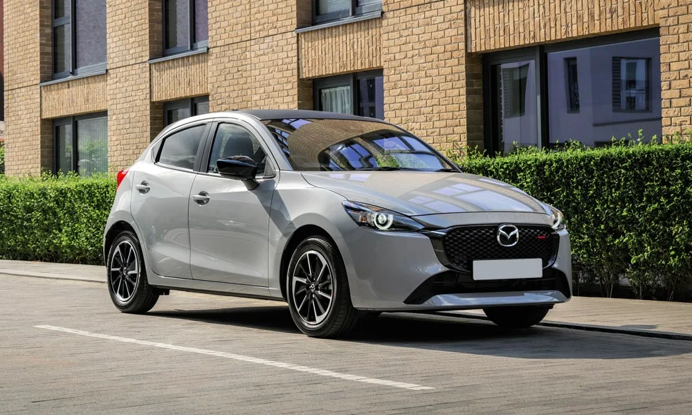 Фото Mazda 2 (2024) — вид спереди, фото 10. Серебристый кузов, строгая симметрия оптики — базовый ракурс знакомства с дизайном Mazda 2 (2024) — вид спереди, фото 10