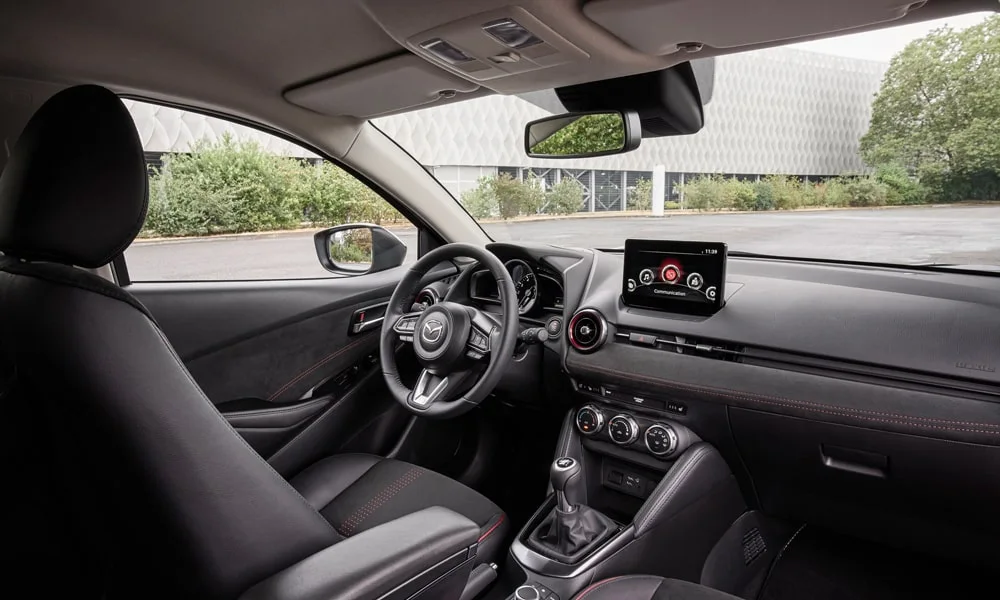 Фото Mazda 2 (2024) — интерьер, фото 2. Общий план салона: архитектура панели, консоль и кресла. Уровень отделки читается по стыкам панелей и мягким поверхностям в зонах касания Mazda 2 (2024) — интерьер, фото 2