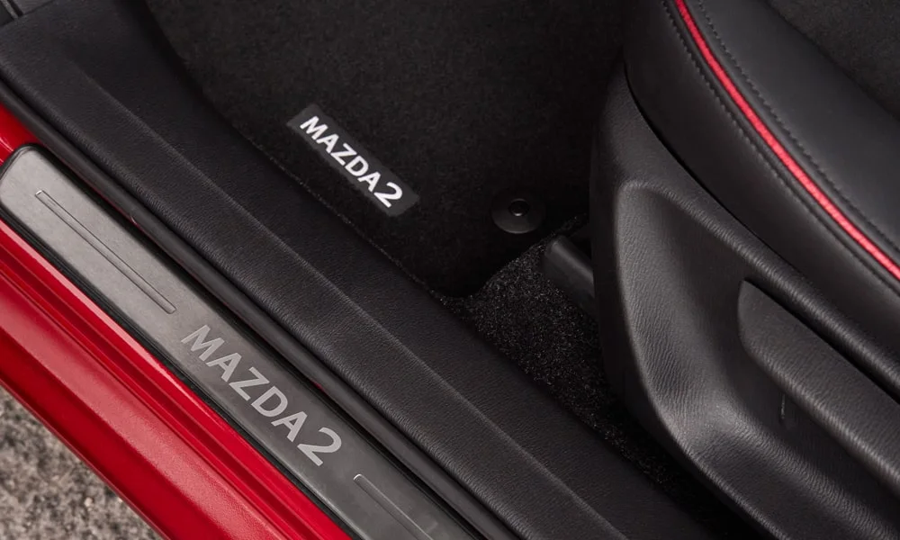 Фото Mazda 2 (2024) — интерьер, фото 3. Общий план салона: архитектура панели, консоль и кресла. Уровень отделки читается по стыкам панелей и мягким поверхностям в зонах касания Mazda 2 (2024) — интерьер, фото 3