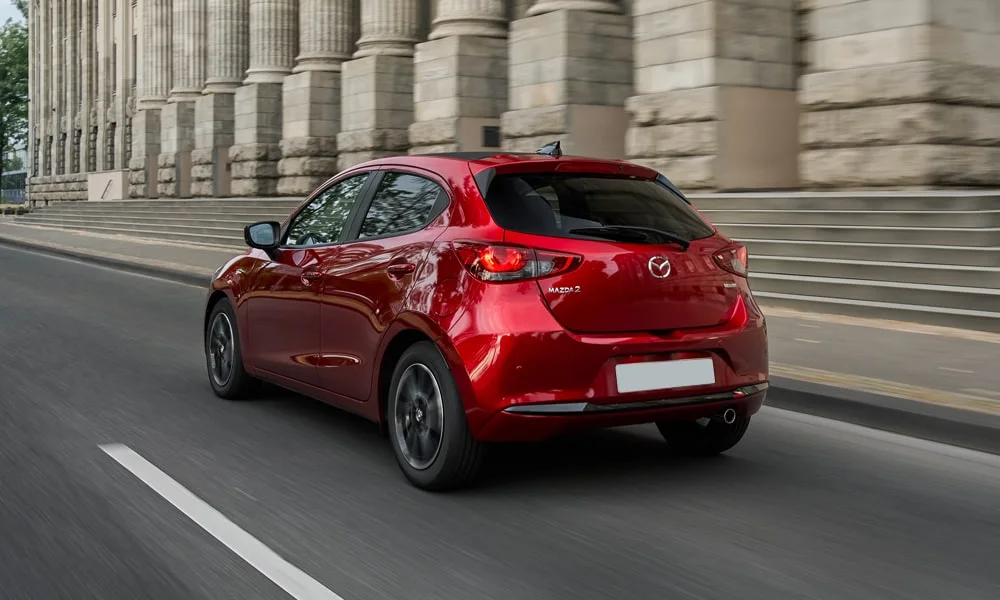 Фото Mazda 2 (2024) — вид сзади, фото 3. Красный кузов сзади — фонари и бампер определяют ночной образ модели. Светодиодная полоса или раздельные секции — задняя оптика стала главным украшением кормы Mazda 2 (2024) — вид сзади, фото 3