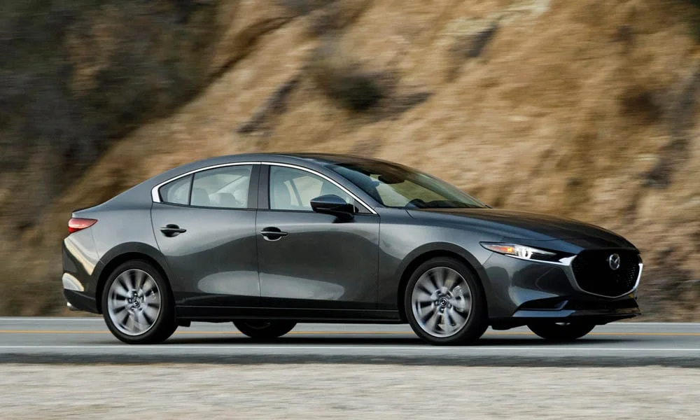 Фото Mazda 3 — вид сбоку, фото 6. Серый кузов в профиль — пропорции, высота посадки и дизайн дисков. Длинная база — простор второго ряда; короткие свесы упрощают парковку Mazda 3 — вид сбоку, фото 6