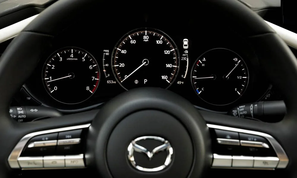 Фото Mazda 3 — руль, фото 4. Обшивка обода и компоновка спиц крупным планом. Правильная посадка: руки на «9 и 3», приборы читаются поверх обода Mazda 3 — руль, фото 4