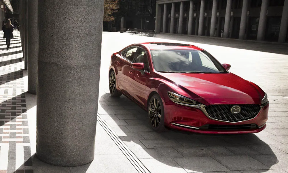 Фото Mazda 6 — вид спереди, фото 4. Красный кузов, строгая симметрия оптики — базовый ракурс знакомства с дизайном. Рисунок ходовых огней — подпись модели, по нему её узнают в потоке Mazda 6 — вид спереди, фото 4