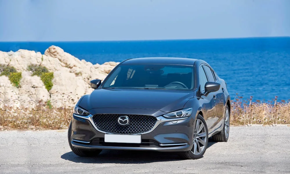 Фото Mazda 6 — вид спереди, фото 7. Серый кузов, строгая симметрия оптики — базовый ракурс знакомства с дизайном. Рисунок ходовых огней — подпись модели, по нему её узнают в потоке Mazda 6 — вид спереди, фото 7