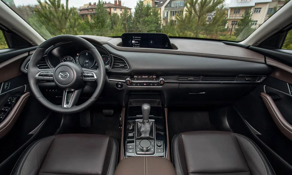 Фото Mazda CX-30 — передняя панель. Архитектура передней панели: ярусы, вставки и консоль в коричневой гамме. Минимум физических кнопок — ставка на экранное управление Mazda CX-30 — передняя панель