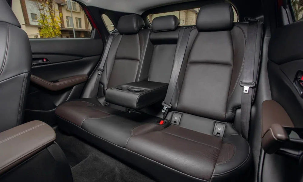 Фото Mazda CX-30 — задние сиденья. Посадка второго ряда: подголовники и подлокотник. Плоский пол упрощает посадку втроём Mazda CX-30 — задние сиденья