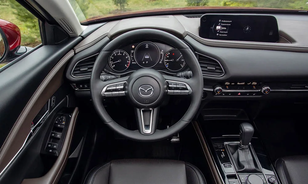 Фото Mazda CX-30 — руль. Обшивка обода и компоновка спиц крупным планом. Клавиши на спицах управляют медиа, круизом и ассистентами — руки остаются на руле Mazda CX-30 — руль