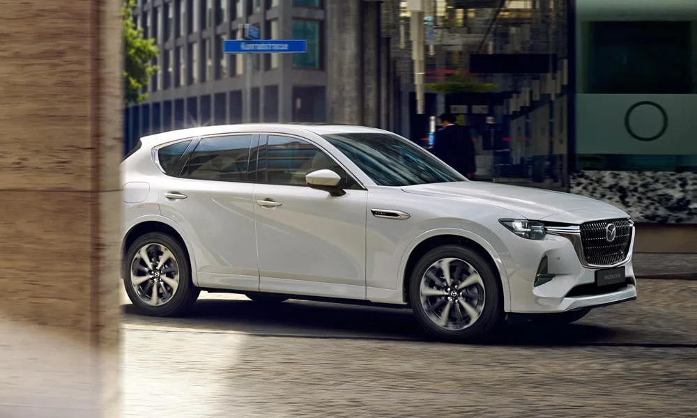 Фото Mazda CX-60 (2024) — вид спереди, фото 3. Кузов в белом цвете: рисунок оптики и решётки задаёт узнаваемое «лицо» модели Mazda CX-60 (2024) — вид спереди, фото 3