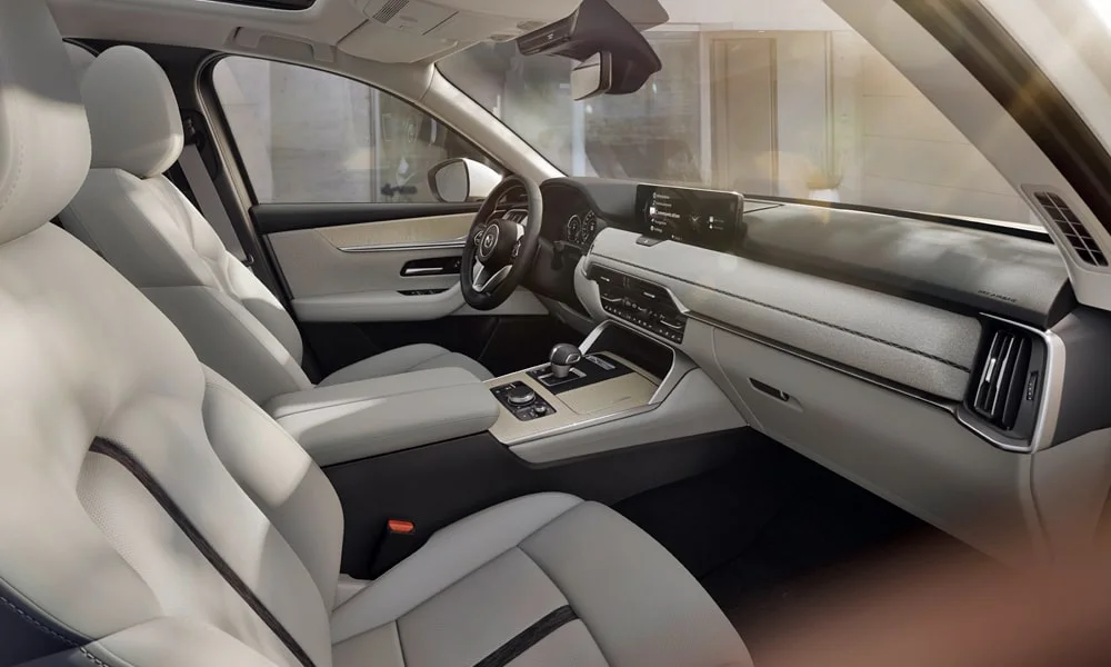 Фото Mazda CX-60 (2024) — интерьер. Общий план салона: архитектура панели, консоль и кресла. Светлая гамма зрительно расширяет салон, тёмная — практичнее в уходе Mazda CX-60 (2024) — интерьер