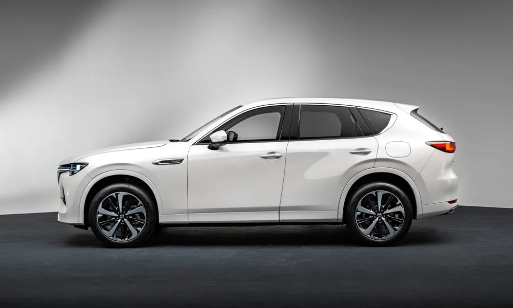 Фото Mazda CX-60 (2024) — вид сбоку, фото 2. Сбоку читаются линия остекления и характер выштамповок на белом кузове. Длинная база — простор второго ряда; короткие свесы упрощают парковку Mazda CX-60 (2024) — вид сбоку, фото 2