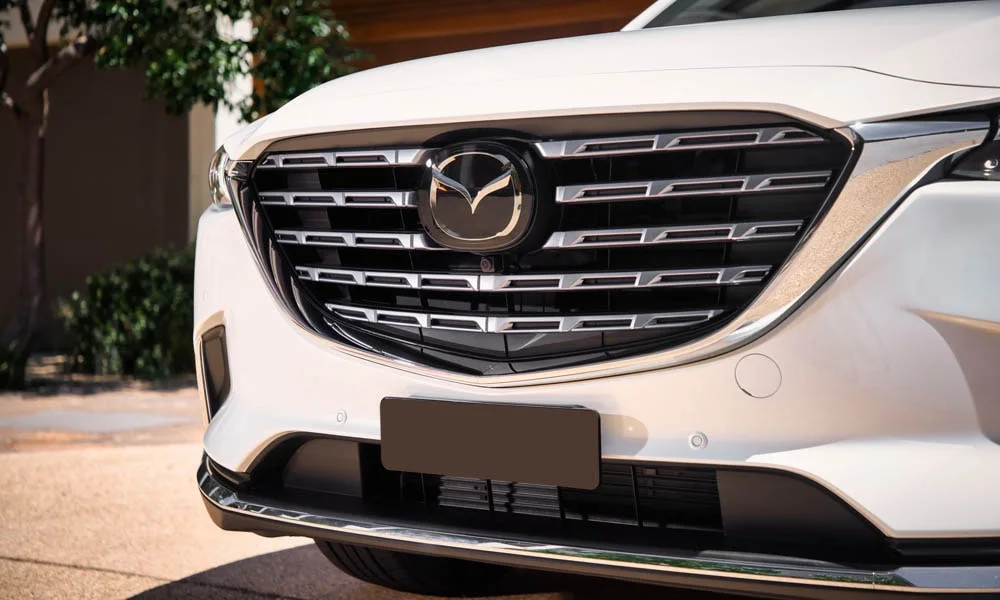 Фото Mazda CX-9 — вид спереди, фото 5. Передок в белом исполнении — крупная светотехника и выразительный бампер. Дневные ходовые огни включаются автоматически с запуском Mazda CX-9 — вид спереди, фото 5